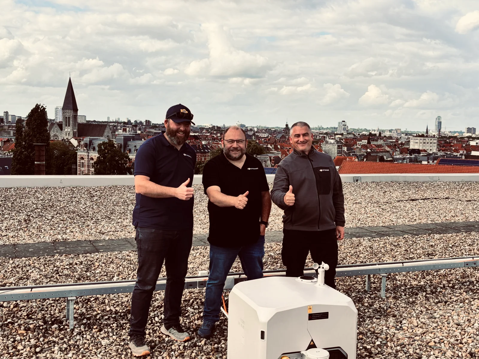 Trois personnes sur un toit avec une station DJI Dock au premier plan